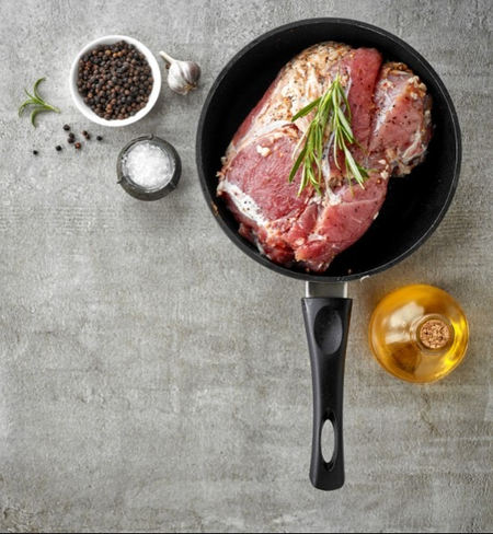 Grass-fed beef arm roast searing in a cast iron skillet with rosemary